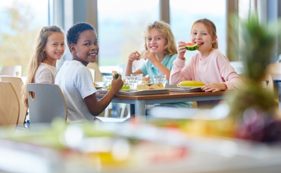 four children sitting togheter eating healthy food