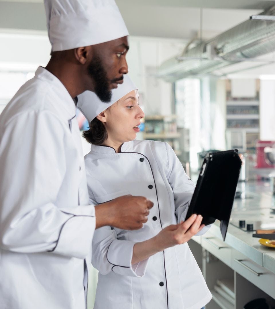 2 cooks looking at a tablet for automated food orders